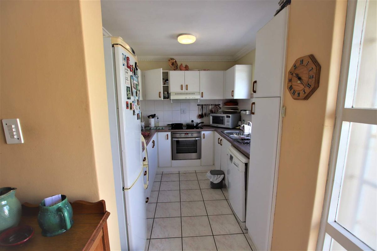 A functional galley-style kitchen featuring white cabinetry, tiled flooring, a built-in oven, and a tiled backsplash.