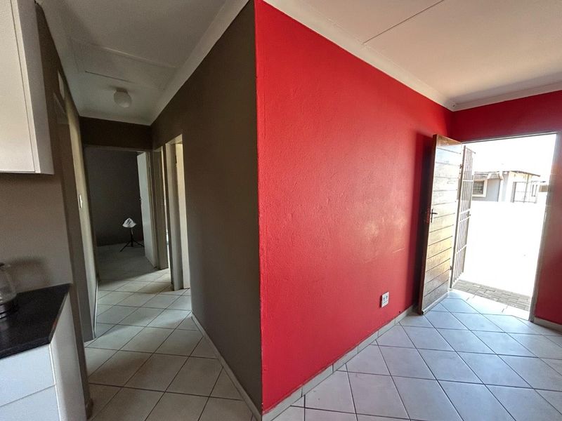 An open-plan living area featuring tiled flooring, a security gate, and direct access to the exterior.