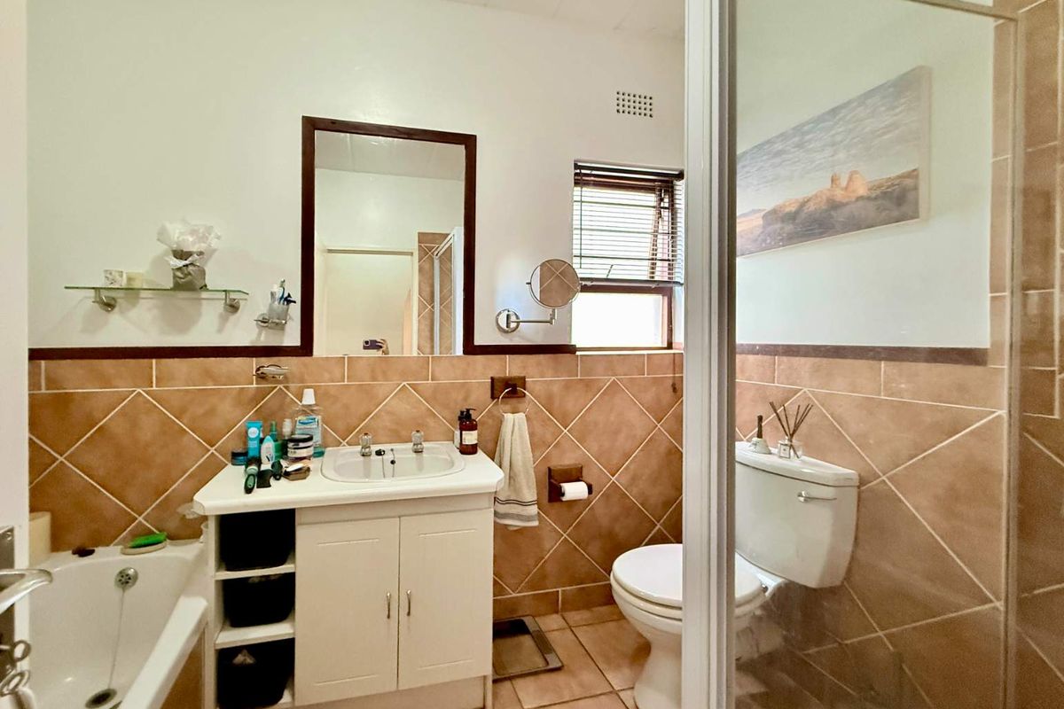 A functional bathroom featuring a vanity with integrated basin, a bathtub, a toilet, and a separate shower enclosure with tiled walls.