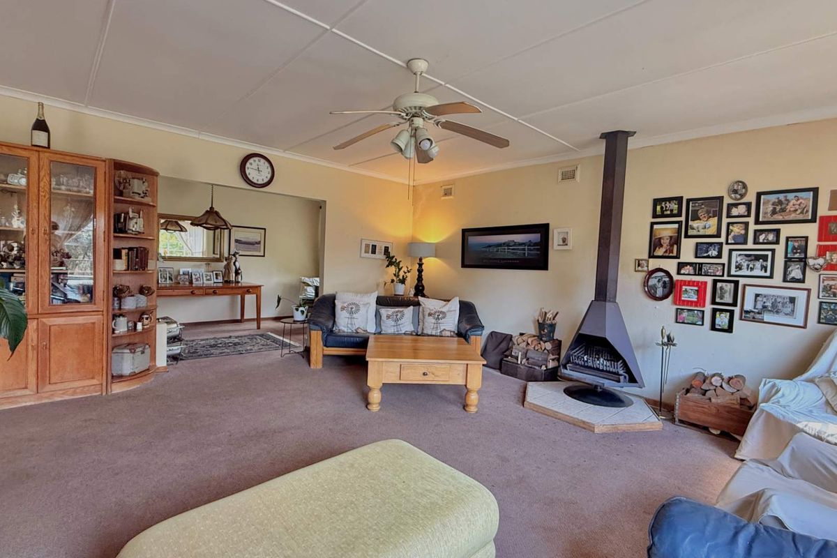 Spacious living room featuring a prominent freestanding fireplace, ceiling fan, and built-in cabinetry, offering a comfortable and functional layout.