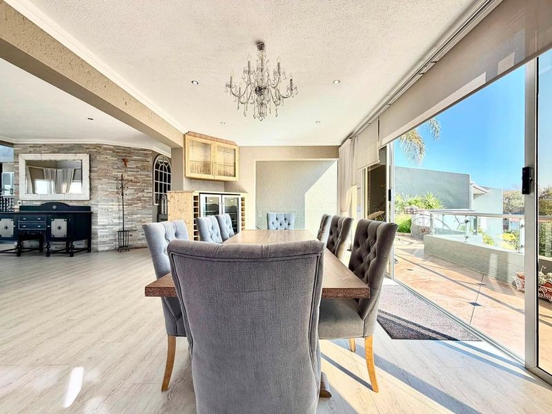 Spacious dining area featuring a stone accent wall, elegant chandelier, and large sliding glass doors providing seamless access to the outdoor patio.