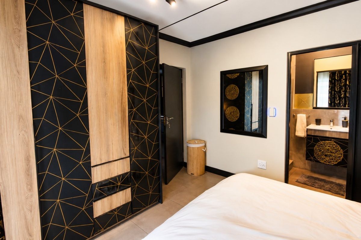 A modern bedroom featuring a large geometric-patterned built-in wardrobe and direct access to an en-suite bathroom with contemporary finishes.