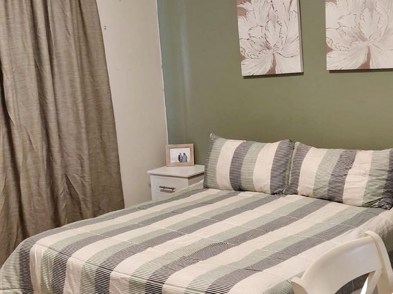 A bedroom featuring tiled flooring and a neutral color palette with an accent wall.