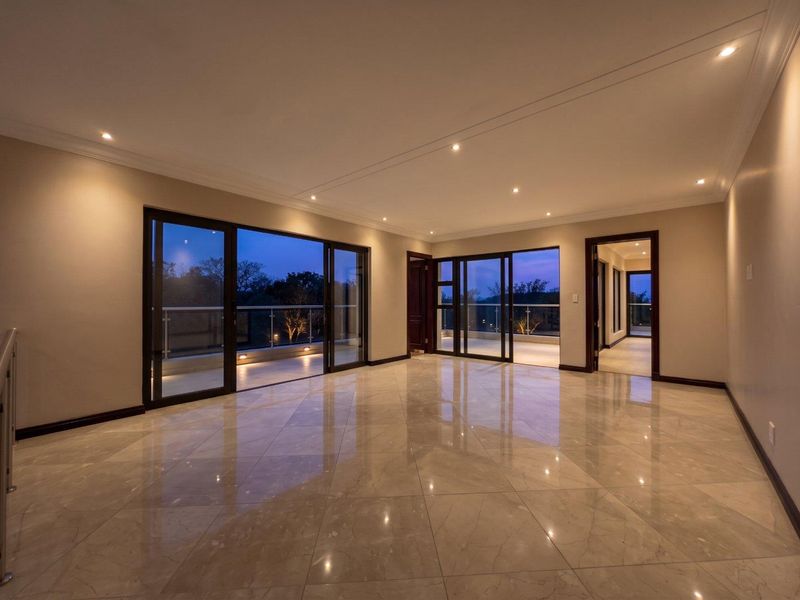 Spacious, modern living area featuring polished porcelain tiles, recessed lighting, and large sliding glass doors opening onto a balcony with a glass balustrade.