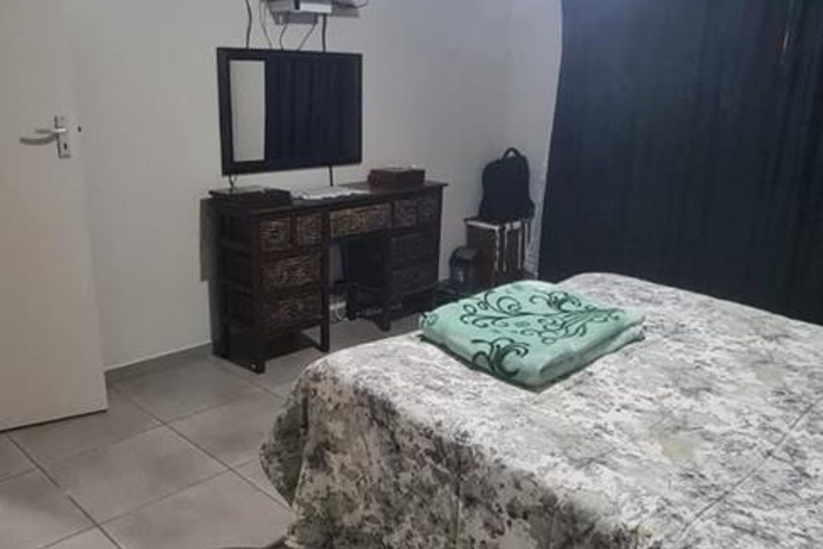 A bedroom featuring tiled flooring and a ceiling fan, providing a functional space with neutral wall finishes.