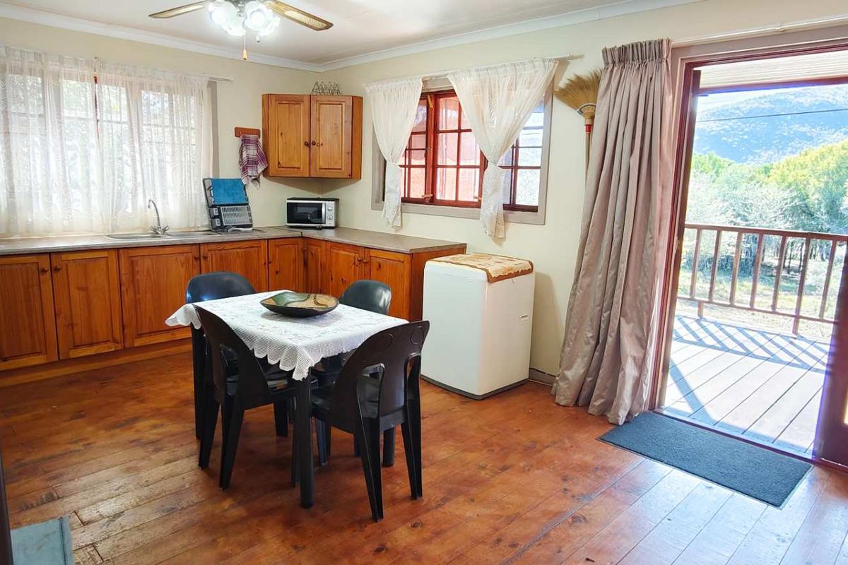 A rustic kitchen featuring timber cabinetry, wooden flooring, and direct access to an outdoor deck area.
