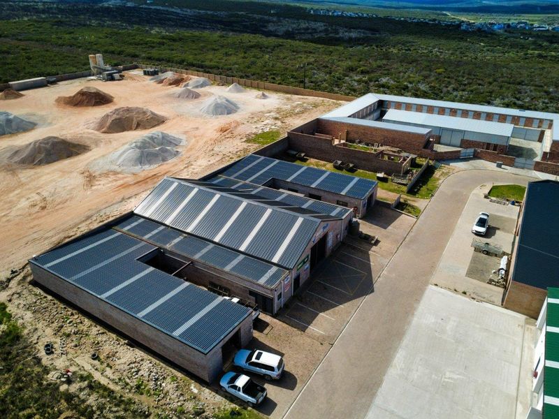 Aerial view of a commercial industrial property featuring multiple warehouse units with solar panel installations and paved access areas.