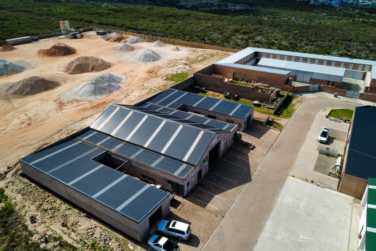 Aerial view of a commercial industrial property featuring multiple warehouse units with solar panel installations and paved access areas.