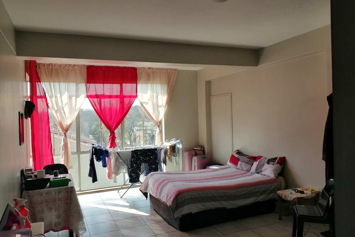A bedroom featuring tiled flooring and a large window providing natural light.