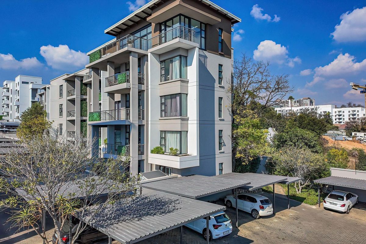 Aerial view of a modern multi-story apartment complex featuring contemporary facade design, private balconies, and covered parking bays.