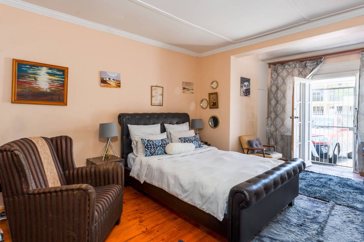 A bedroom featuring polished timber flooring, crown molding, and direct access to an outdoor area through a glass-paneled door.