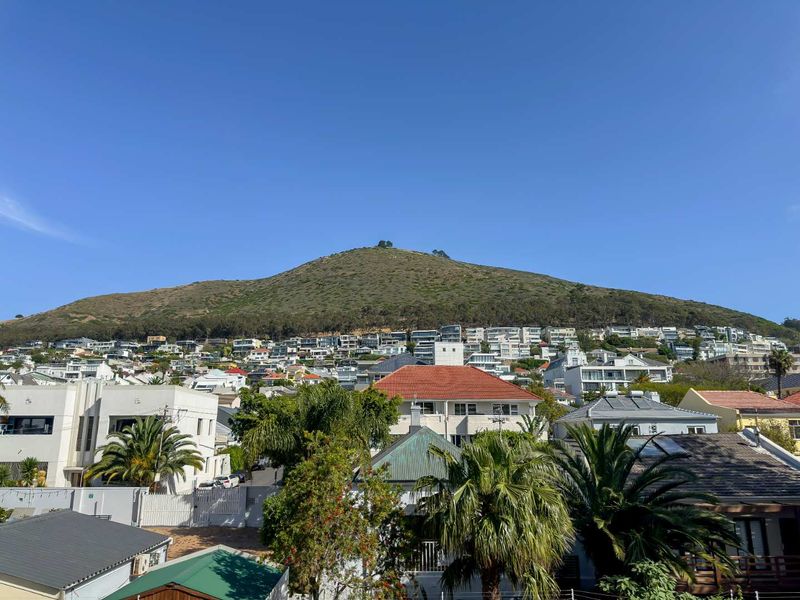 A clear, elevated view of the surrounding residential neighbourhood with a prominent mountain backdrop under a bright blue sky.