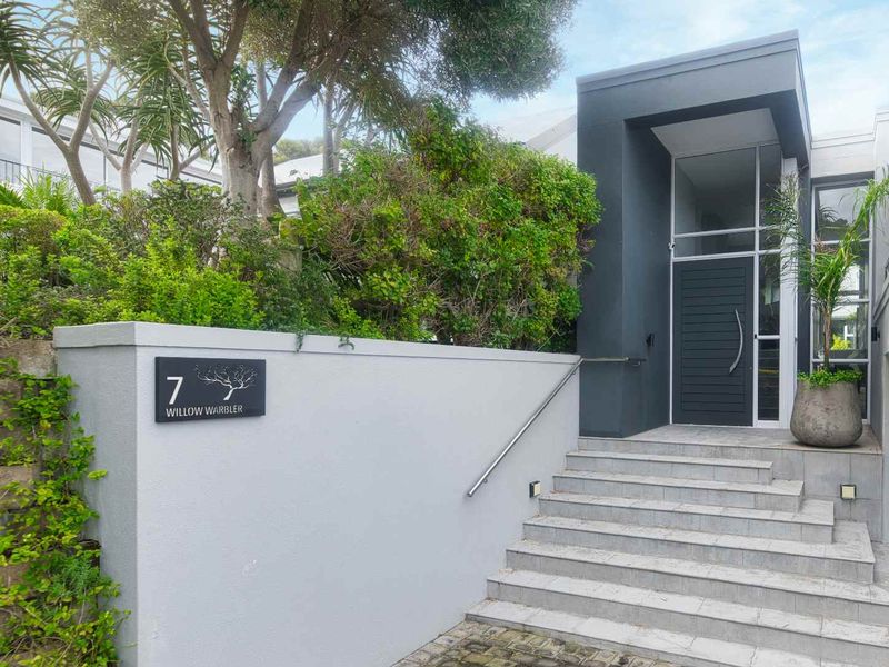 Modern front entrance featuring a concrete staircase with a metal handrail, leading to a contemporary dark-toned front door and glass entryway.