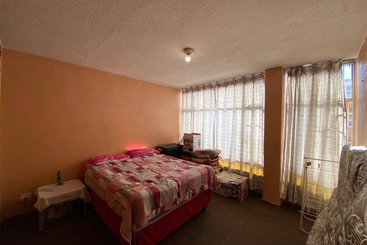 A bedroom featuring large windows with natural light, textured ceiling, and wall space ready for a modern update.