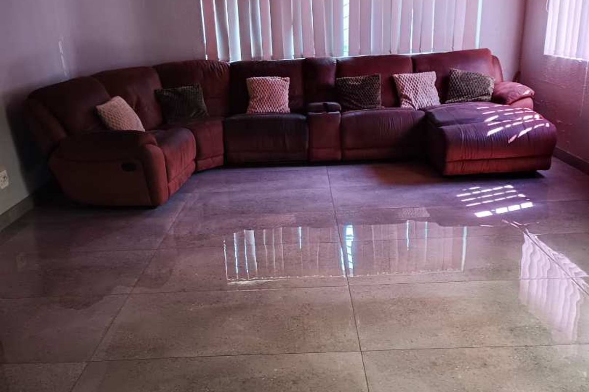 Spacious living room featuring large format floor tiles and a warm timber tongue and groove ceiling with integrated lighting.