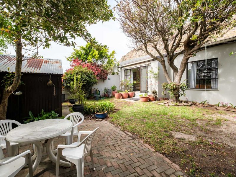 A private rear garden featuring a brick-paved patio area, mature trees, and a detached storage shed, offering potential for landscaping and outdoor living.