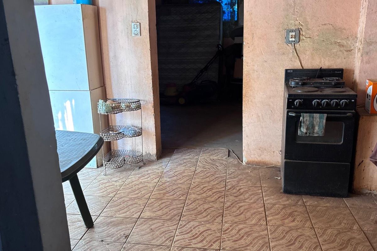 A dated kitchen area featuring tiled flooring, a freestanding stove, and visible wall deterioration, requiring significant renovation and cosmetic updates.