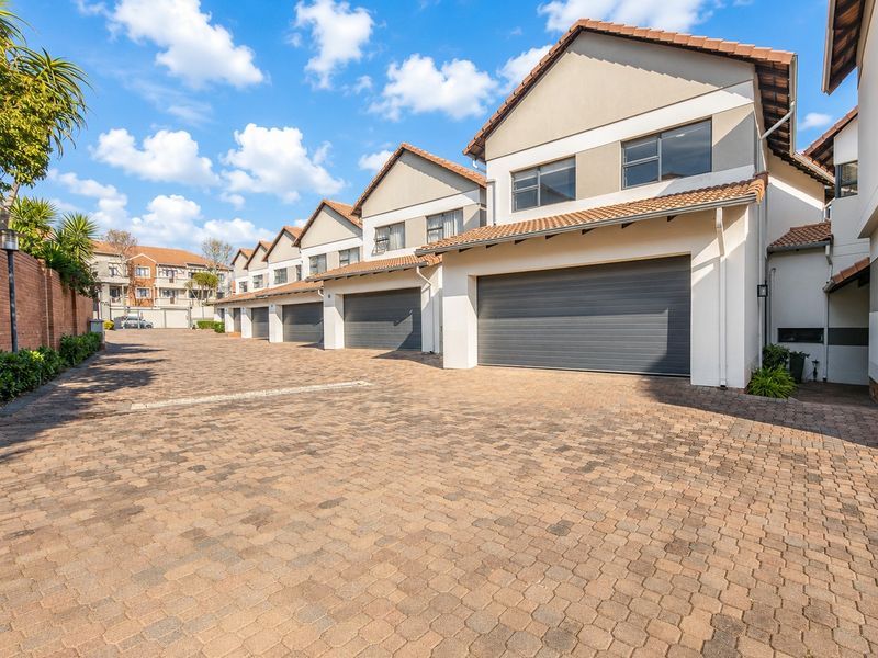 A well-maintained townhouse complex featuring paved driveway access and multiple individual garage units with tiled roofing.