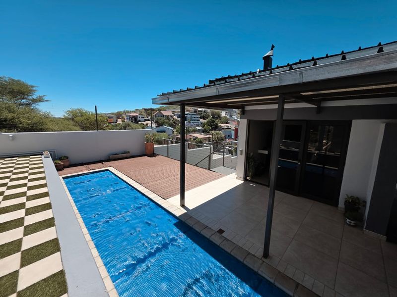 Outdoor entertainment area featuring a swimming pool with cover, timber decking, and a covered patio space with direct access to the home.