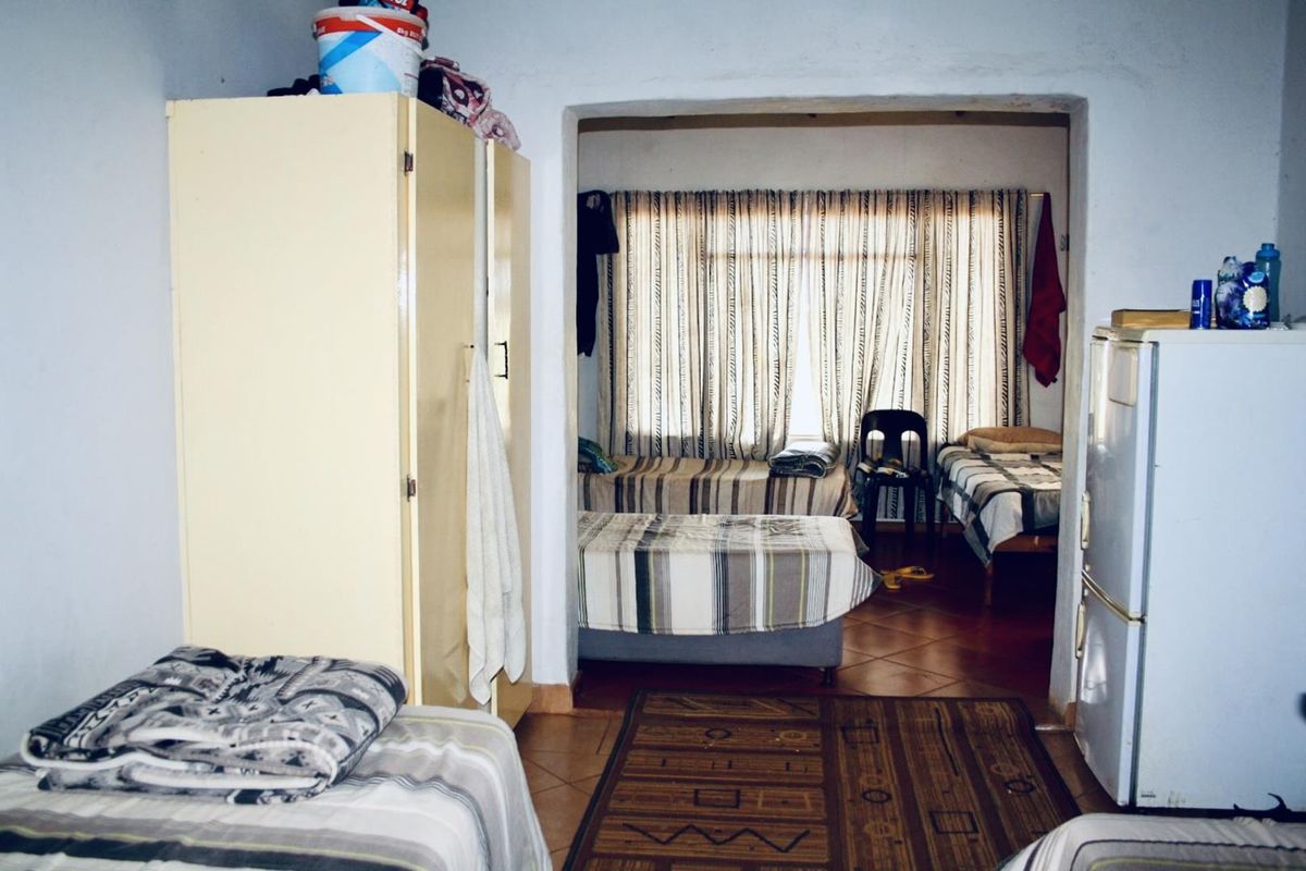 A multi-purpose bedroom area featuring tiled flooring and a connecting doorway, providing functional sleeping space within the farm property.
