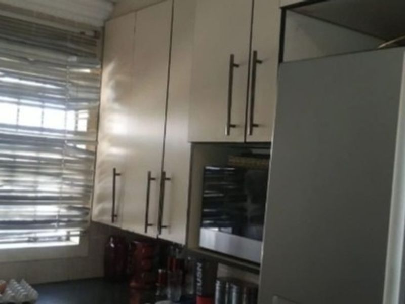 A functional kitchen area featuring built-in cabinetry, a window with security bars, and a built-in microwave.