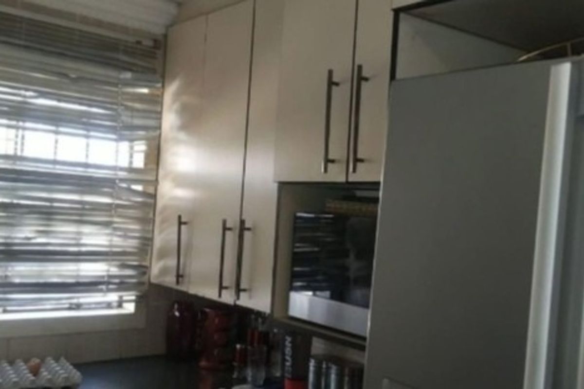 A functional kitchen area featuring built-in cabinetry, a window with security bars, and a built-in microwave.