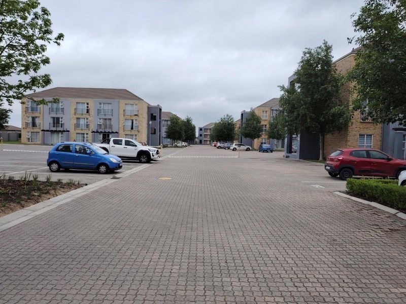 View of the apartment complex exterior featuring paved parking areas and multi-story residential buildings with balconies.
