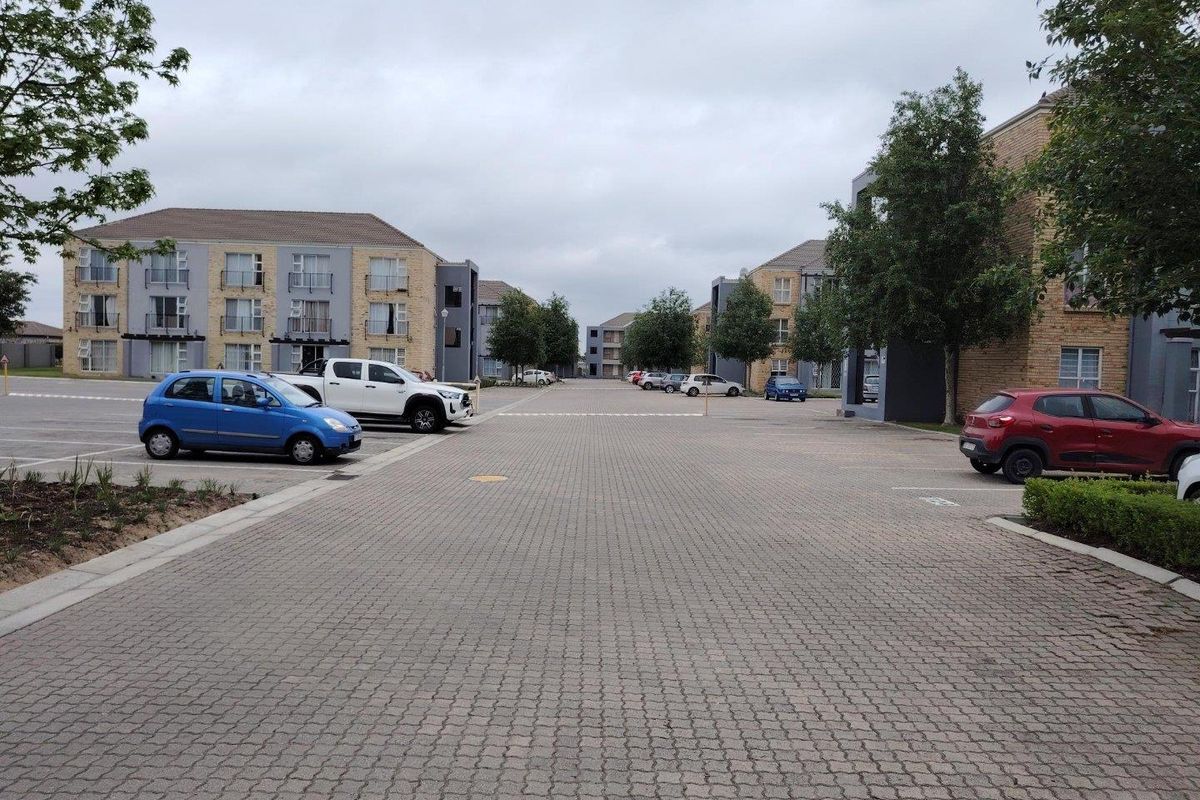 View of the apartment complex exterior featuring paved parking areas and multi-story residential buildings with balconies.