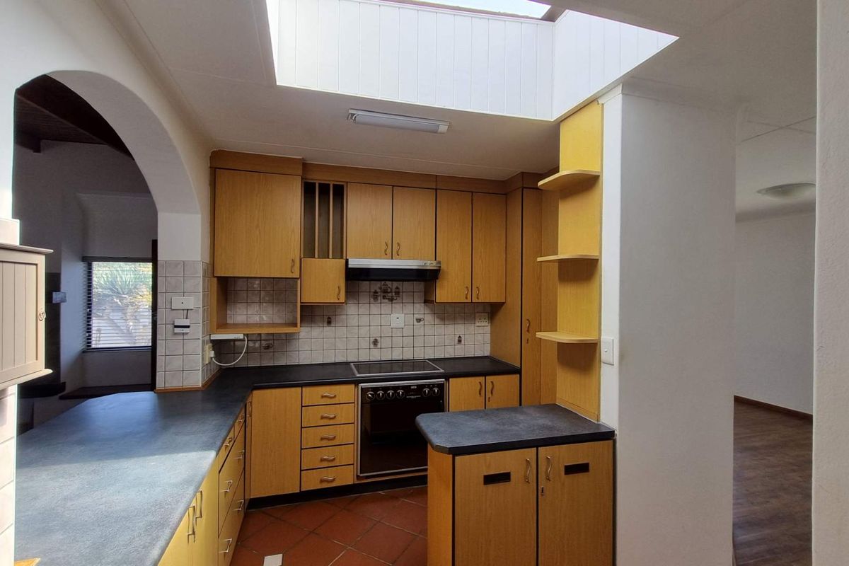 A functional kitchen featuring built-in wooden cabinetry, laminate countertops, a built-in oven with hob, and a skylight providing natural light.