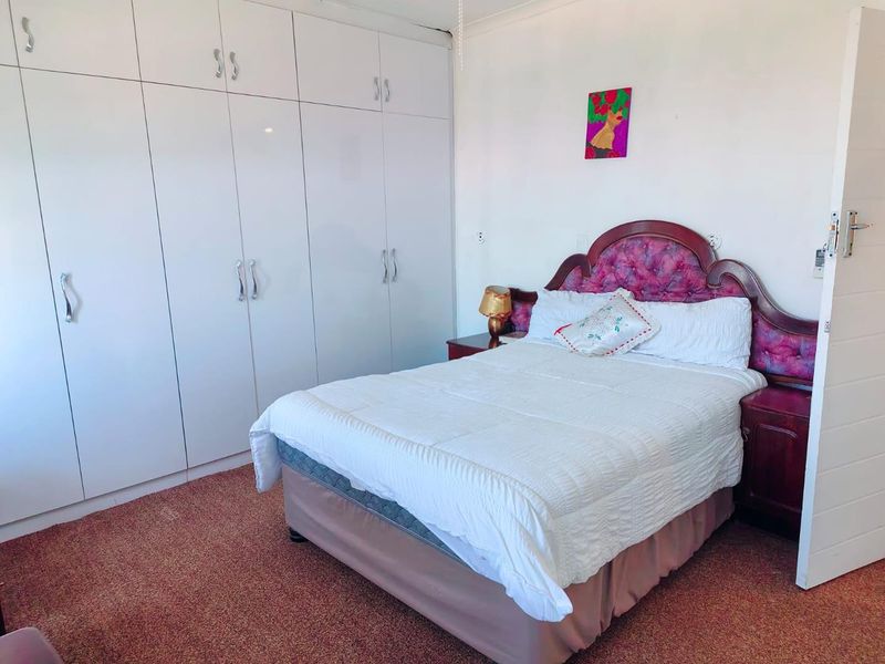 A bedroom featuring extensive white built-in cupboards and carpeted flooring.