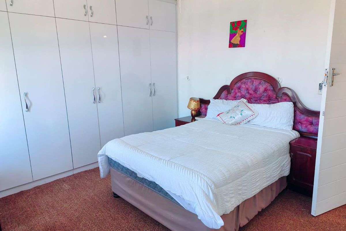 A bedroom featuring extensive white built-in cupboards and carpeted flooring.