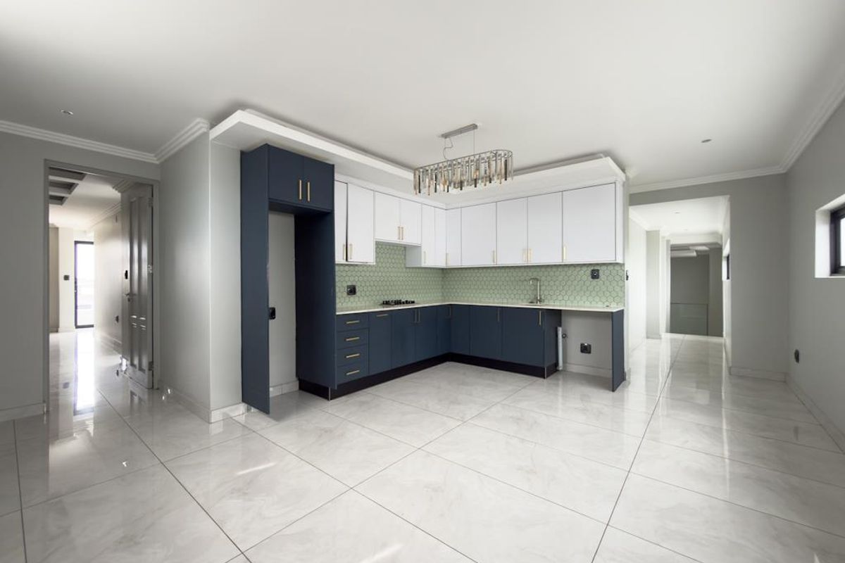 Modern kitchen featuring two-tone cabinetry, a hexagonal tile backsplash, integrated hob, and polished marble-look floor tiles in an open-plan layout.