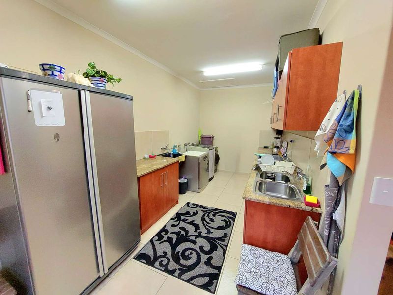 Functional laundry room featuring built-in cabinetry, granite countertops, and a double stainless steel sink with tiled flooring.