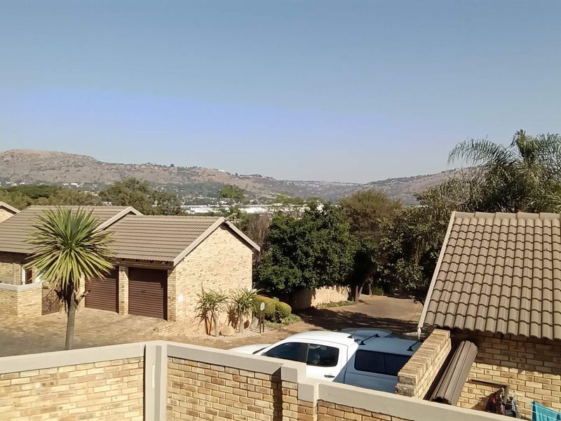 An elevated view overlooking the townhouse complex rooftops, surrounding landscape, and distant hills.