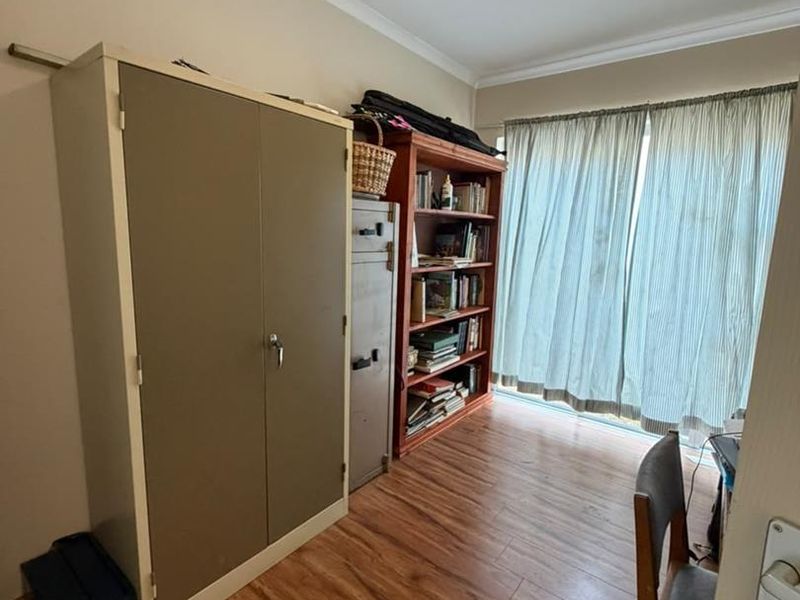 A bedroom featuring laminate flooring, coving, and a ceiling light fixture, currently utilized as a home office or storage space.