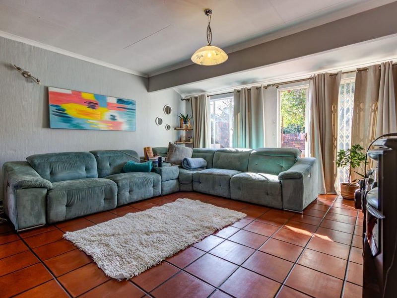 A comfortable living room featuring terracotta floor tiles, neutral walls, and sliding glass doors that provide access to the outdoor area.