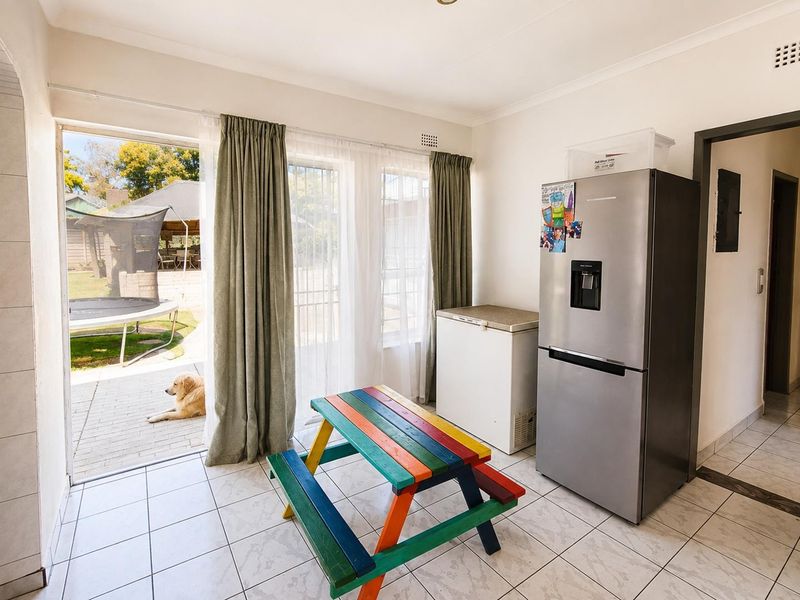 A functional utility or scullery area featuring tiled flooring and direct access to the rear patio through a sliding glass door.