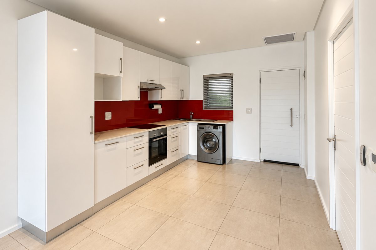 Modern kitchen featuring white high-gloss cabinetry, a striking red glass splashback, integrated appliances, and neutral tiled flooring in an open-plan layout.
