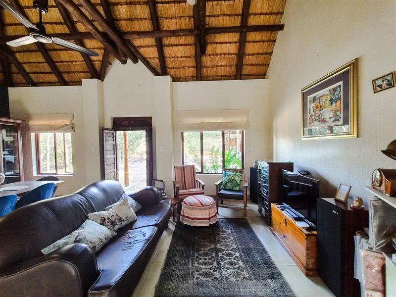 Spacious living room featuring a high vaulted thatched ceiling with exposed timber rafters, tiled flooring, and direct access to the exterior.