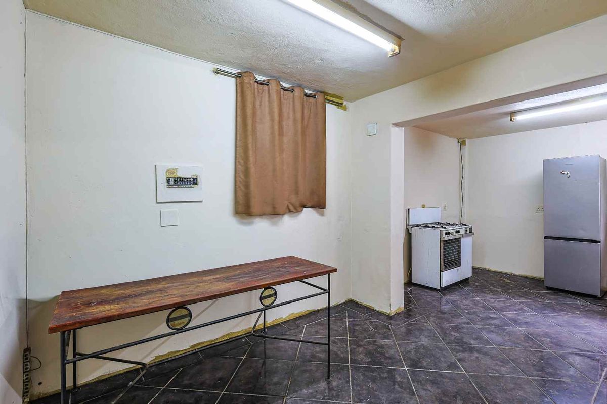 A basic kitchen area featuring dark floor tiles, a freestanding stove, and simple wall finishes, offering a functional space ready for renovation.