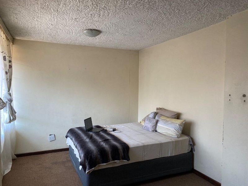 A bedroom featuring textured ceilings, carpeted flooring, and neutral wall finishes, requiring cosmetic updates to improve its overall condition and appeal.