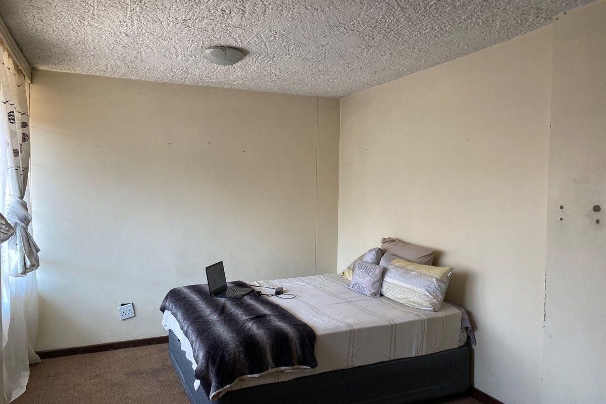 A bedroom featuring textured ceilings, carpeted flooring, and neutral wall finishes, requiring cosmetic updates to improve its overall condition and appeal.