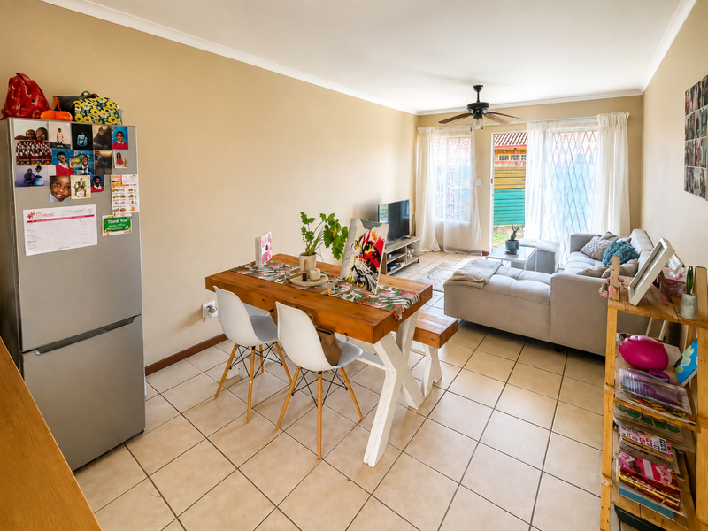 Open-plan living and dining area featuring tiled flooring, a ceiling fan, and a sliding glass door providing access to the exterior.