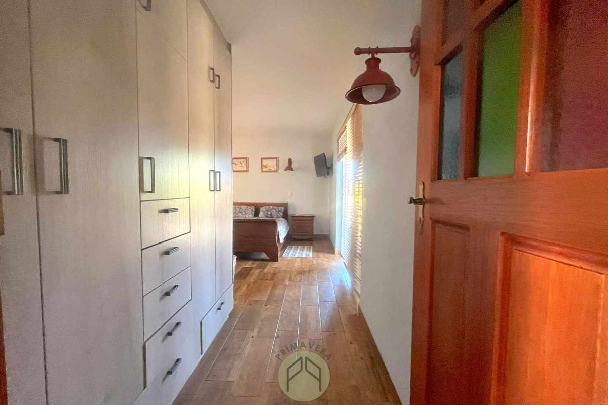 A bedroom featuring built-in floor-to-ceiling cabinetry, wooden flooring, and a warm, inviting atmosphere with natural light.