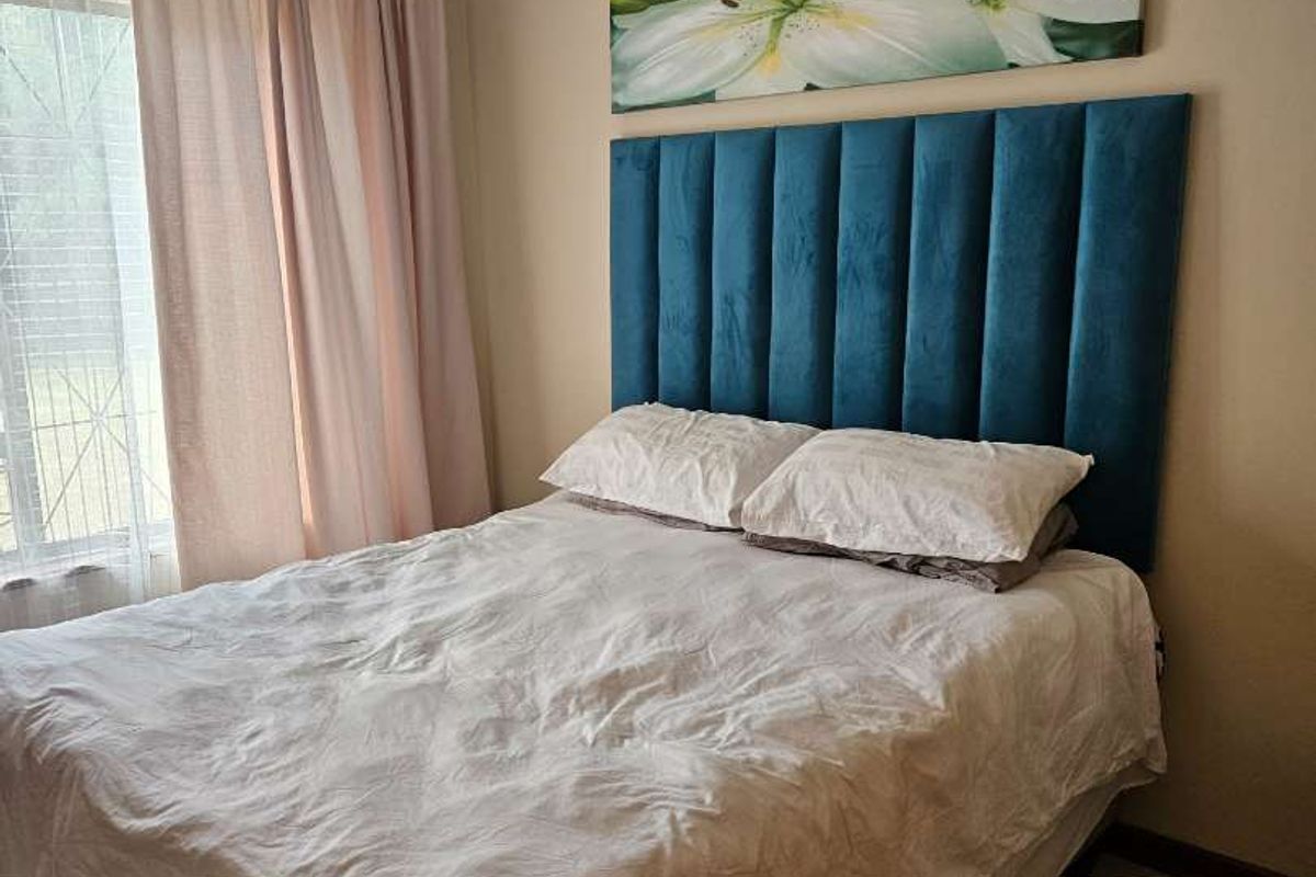 A cozy bedroom featuring tiled flooring and a window with curtains, providing a comfortable and functional sleeping space.