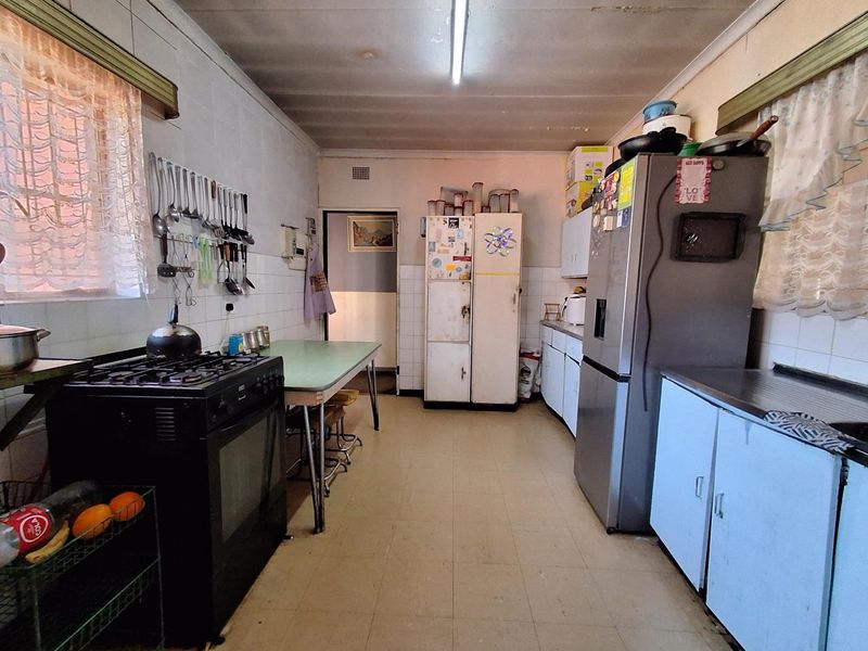 A functional kitchen featuring dated cabinetry, tiled splashbacks, and a gas stove, offering significant potential for modernization and renovation.