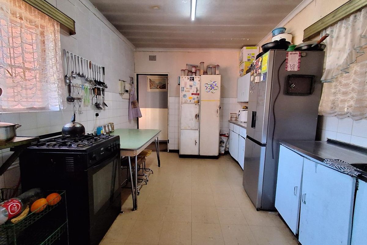 A functional kitchen featuring dated cabinetry, tiled splashbacks, and a gas stove, offering significant potential for modernization and renovation.