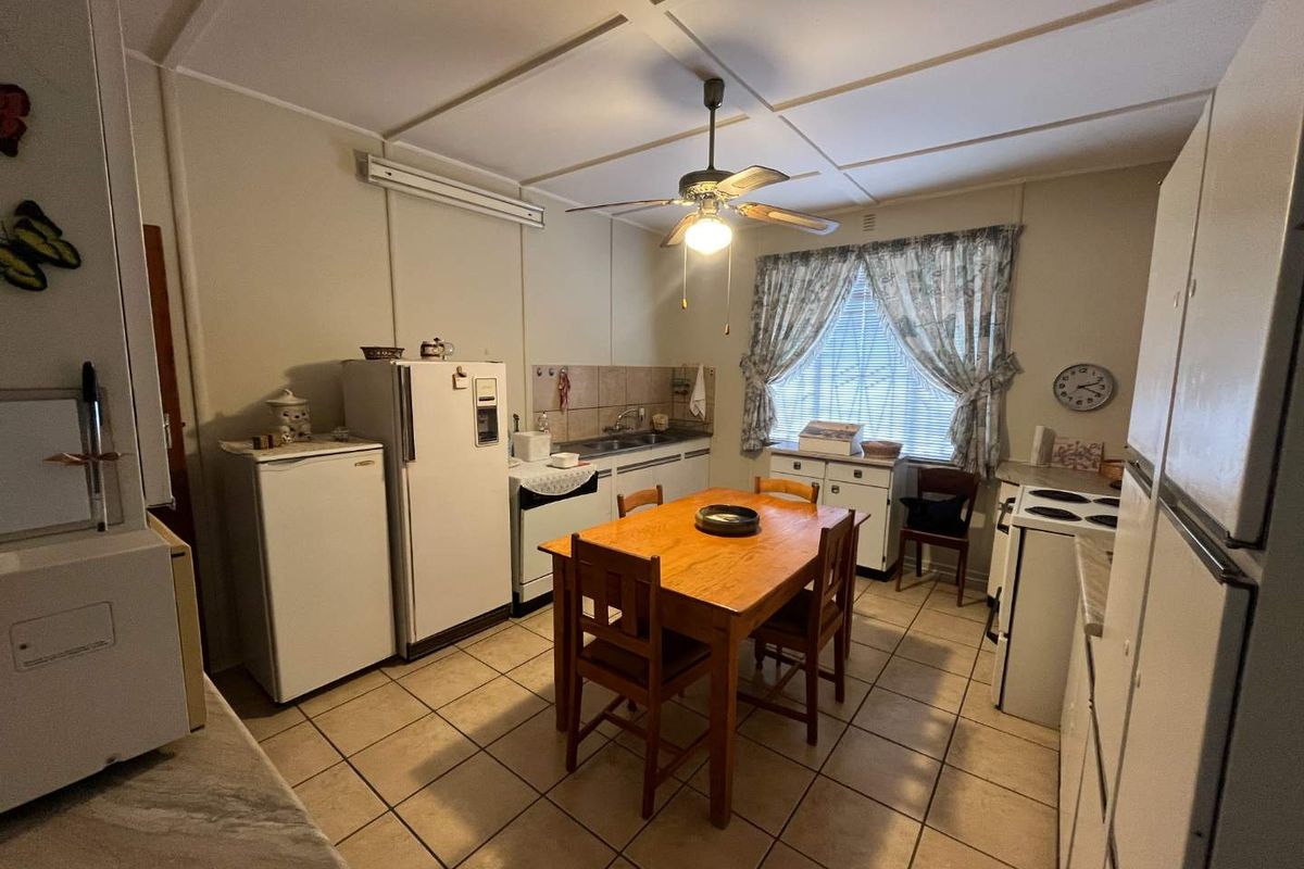 A functional kitchen and dining area featuring tiled flooring, built-in cabinetry, and a ceiling fan, offering a practical layout for daily meals.