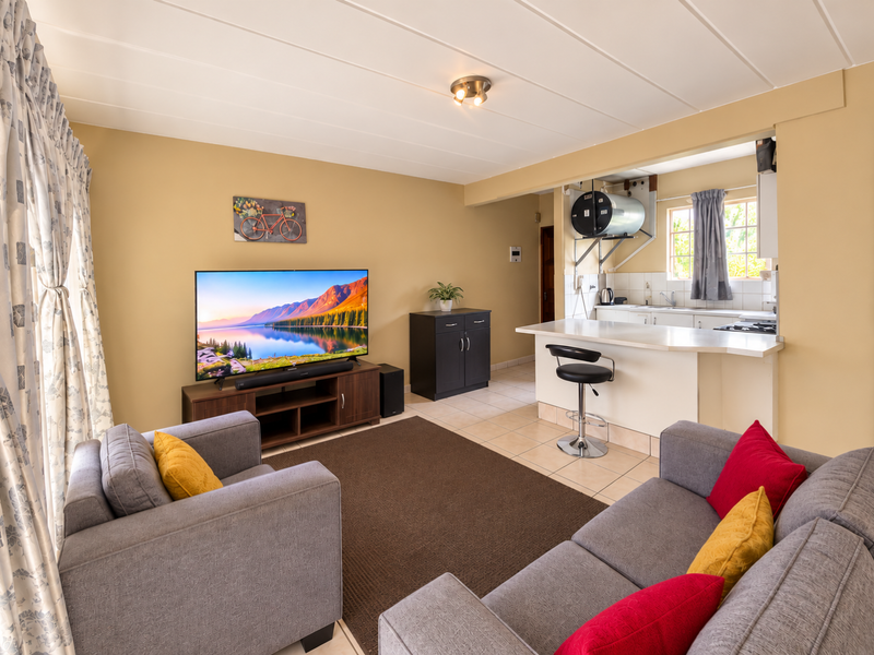 Open-plan living area featuring a breakfast bar, tiled flooring, and a functional kitchen space with an exposed water heater.