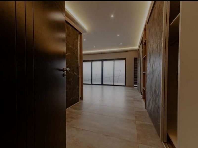Spacious bedroom featuring modern tiled flooring, built-in wardrobes, recessed ceiling lighting, and large sliding glass doors leading to an outdoor area.